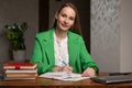 Satisfied teacher writes notes in exercise book at table Royalty Free Stock Photo