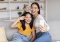 Satisfied teenage girl and young asian female have fun together, make selfie on smartphone