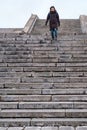 Satisfied tourist in warm clothes and with a city backpack goes down the old stone steps of a dangerous staircase Royalty Free Stock Photo