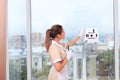 A satisfied uniformed maid remotely controls a window cleaner robot. Room service. Cleaning in the hotel or in the house. Copy of