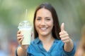 Satisfied woman holding a smoothie with thumbs up