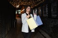 Satisfied woman shopper walks with paper shopping bags along the evening street Royalty Free Stock Photo