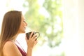 Satisfied woman smelling coffee cup at home