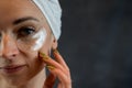 Satisfied woman in white towel applying eye patches for puffiness, wrinkles Royalty Free Stock Photo