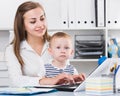 Satisfied woman 22-27 years old is productively working behind laptop with child Royalty Free Stock Photo