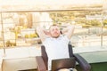 Satisfied with work done. Cheerful young man holding hands behind head and keeping eyes closed while sitting on the terrace with U