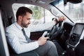 Satisfied young business man looking at mobile phone while driving a car Royalty Free Stock Photo