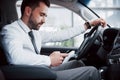 Satisfied young business man looking at mobile phone while driving a car Royalty Free Stock Photo