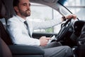 Satisfied young business man looking at mobile phone while driving a car Royalty Free Stock Photo