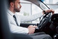 Satisfied young business man looking at mobile phone while driving a car Royalty Free Stock Photo