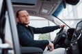 Satisfied young business man looking at mobile phone while driving a car Royalty Free Stock Photo