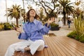 Satisfied young caucasian girl with phone closing her eyes resting sitting on bench in springtime. Royalty Free Stock Photo