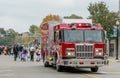 a bright red fire engine heads a parade of halloween kids