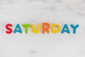 Saturday word written with colorful letters on white marble stone background Royalty Free Stock Photo