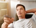 Saturdays are his couch potato days. a young man using a remote control to change the channel on his television while he Royalty Free Stock Photo