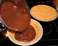 Pouring chocolate into pie pan filled with graham cracker crust Royalty Free Stock Photo