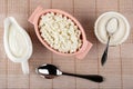 Sauceboat with sour cream, pink bowl with cottage cheese, teaspoon in bowl with sugar, spoon on napkin. Top view Royalty Free Stock Photo