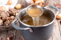 Saucepan with bouillon with a ladle on a wooden table. Bone broth