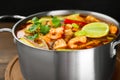 Saucepan with delicious Tom Yum soup on wooden board, closeup Royalty Free Stock Photo