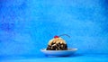 Saucer with a biscuit cake in chocolate crust and ripe cherries on a blue background