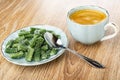 Saucer with marmalade in form green bean, spoon, coffee in blue cup on wooden table Royalty Free Stock Photo