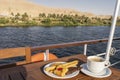 A saucer with cupcakes, pastries and a cup of coffee stands on a wooden table on the deck of a cruise liner. Royalty Free Stock Photo