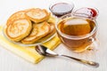 Saucer with pancakes on napkin, bowls with jam, tea, spoon