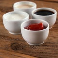 Sauces ketchup, mustard, mayonnaise, sour cream, soy sauce in clay bowls on wooden background