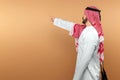 A Saudi Arab man in national dress points his finger at free space. Dishdasha, kandora, thobe, islam. Copy space