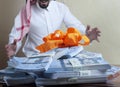 Saudi Arab man surprized with stacks of money on the table