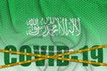 Saudi Arabia flag and Covid-19 inscription with orange quarantine border tape. Coronavirus or 2019-nCov virus concept Royalty Free Stock Photo