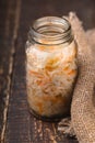 Sauerkraut in a glass jar and rustic napkin on wooden boards