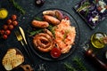 Sauerkraut and grilled sausages with rosemary and cranberries on a black plate. Traditional German dish. Royalty Free Stock Photo