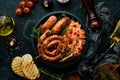 Sauerkraut and grilled sausages with rosemary and cranberries on a black plate. Traditional German dish. Royalty Free Stock Photo