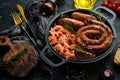 Sauerkraut and grilled sausages with rosemary and cranberries on a black plate. Traditional German dish. Royalty Free Stock Photo