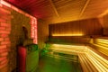 sauna interior with a large brick wall and natural wood trim, stove with stones to humidify air and steam, atmospheric