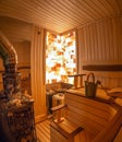 Sauna from wood. Stone wall with lighting from the inside. Classic accessories for bath. Ladle and bucket, stove with hot rocks Royalty Free Stock Photo