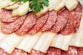 Sausage and bacon dish, garnished with herbs. Sliced meat products lie on a plate in rows. Close-up Royalty Free Stock Photo