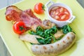 Sausage bratwurst with bacon, baked beans, spinach, tomato