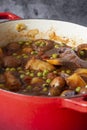 Sausage casserole in a red casserole dish, with potato, mushrooms, tomatoes, peas and onion Royalty Free Stock Photo