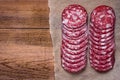 Sausage cut into circles on the paper. Natural wooden background.