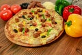 Sausage and minced meat pizza pie with bell pepper, tomato and black olive served in wooden board isolated on table side view of Royalty Free Stock Photo