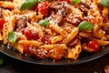 Sausage penne Pasta with tomato sauce, parmesan cheese and basil on black plate Royalty Free Stock Photo