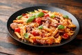 Sausage penne Pasta with tomato sauce, parmesan cheese and basil on black plate Royalty Free Stock Photo