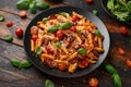 Sausage penne Pasta with tomato sauce, parmesan cheese and basil on black plate Royalty Free Stock Photo