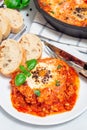 Sausage Shakshuka with eggs, Italian sausage, tomato sauce, on a white plate, vertical