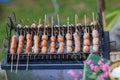 Sausage small circles on the grid-iron grill with smoke over charcoal.