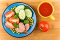 Sausage and vegetables in blue plate, tomato juice in cup