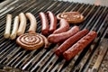 Sausages assortment grilling on metal grill.