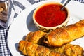 Sausages baked in dough sprinkled with salt and poppy seeds and bowl with tomatoes sauce in a rustic composition. Sausages rolls, Royalty Free Stock Photo